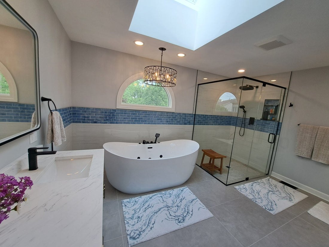 Bright, modern bathroom with a freestanding tub, glass walk-in shower, blue tile accent wall, and natural light from an arched window and skylight.