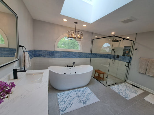 Bright, modern bathroom with a freestanding tub, glass walk-in shower, blue tile accent wall, and natural light from an arched window and skylight.