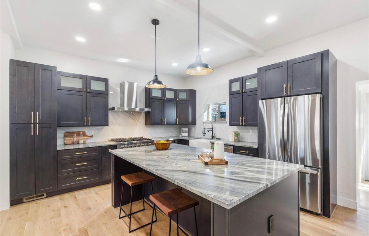 Kitchen remodel with dark charcoal shaker cabinets, granite waterfall island, brass hardware, marble backsplash, and light hardwood floors