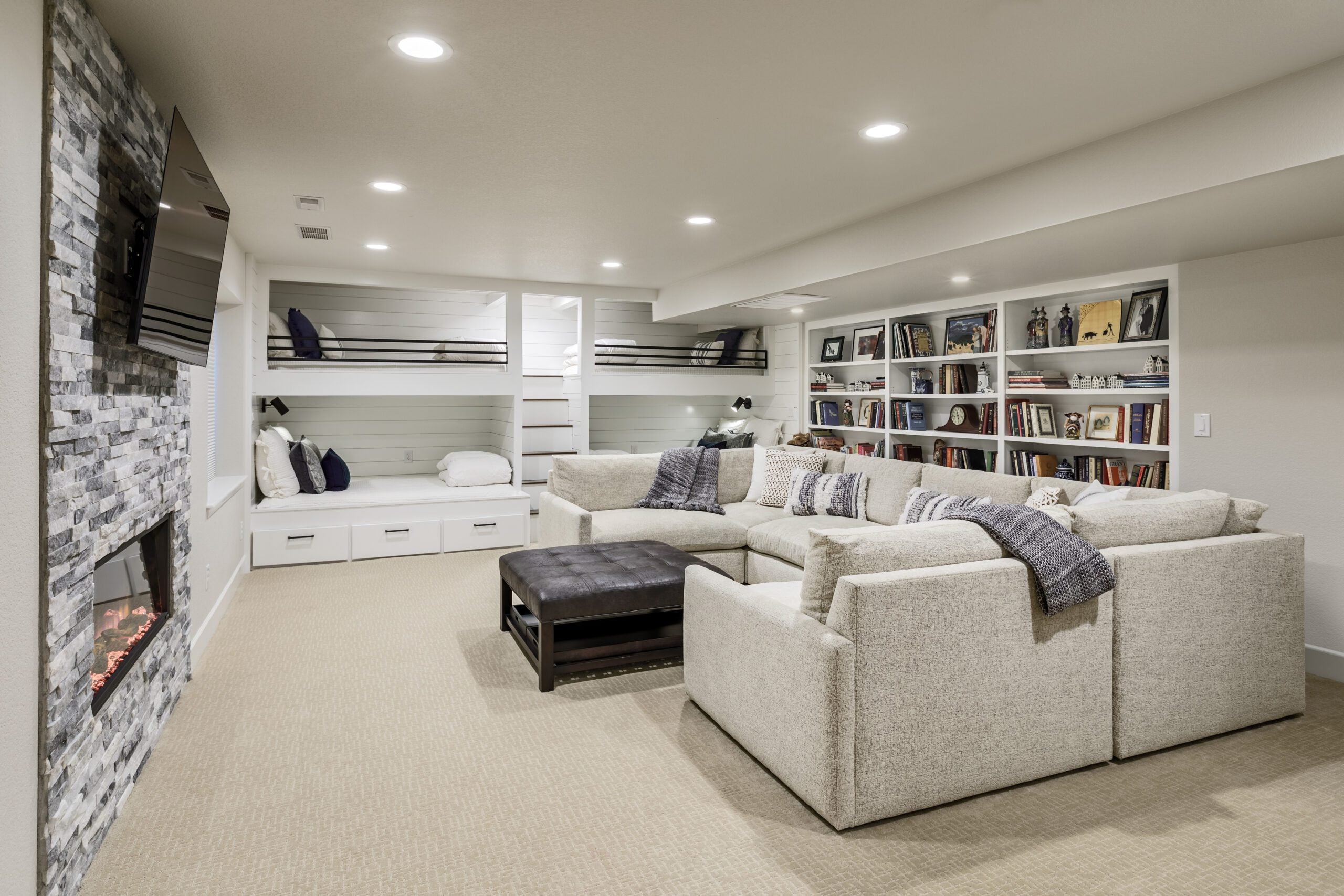 Modern living room with a large sectional sofa, bookshelf, and fireplace
