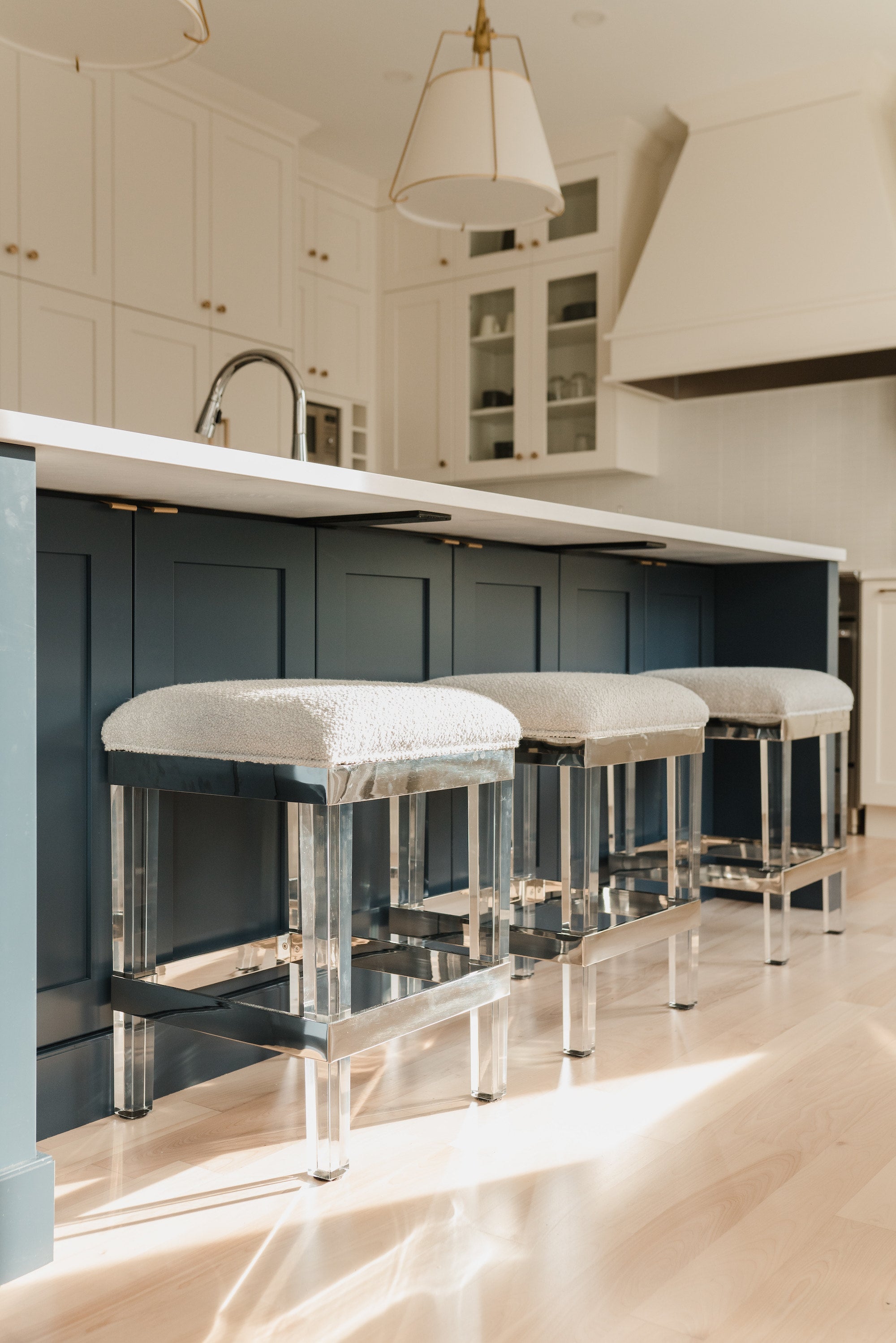 Modern kitchen with blue cabinets, white countertops, and decorative stools