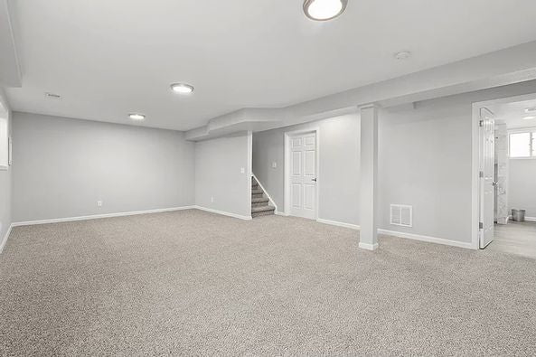 Empty basement with gray carpet, white walls, and a staircase