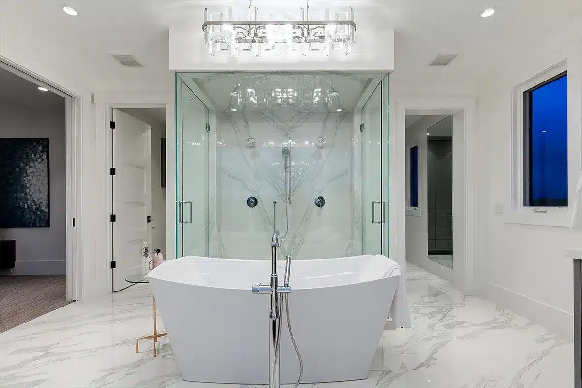 Modern bathroom with freestanding bathtub, glass shower enclosure, and chandelier
