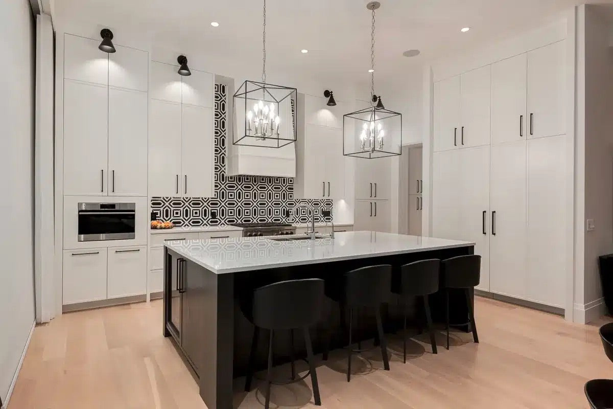 Modern kitchen with white cabinets, black island, and black chairs