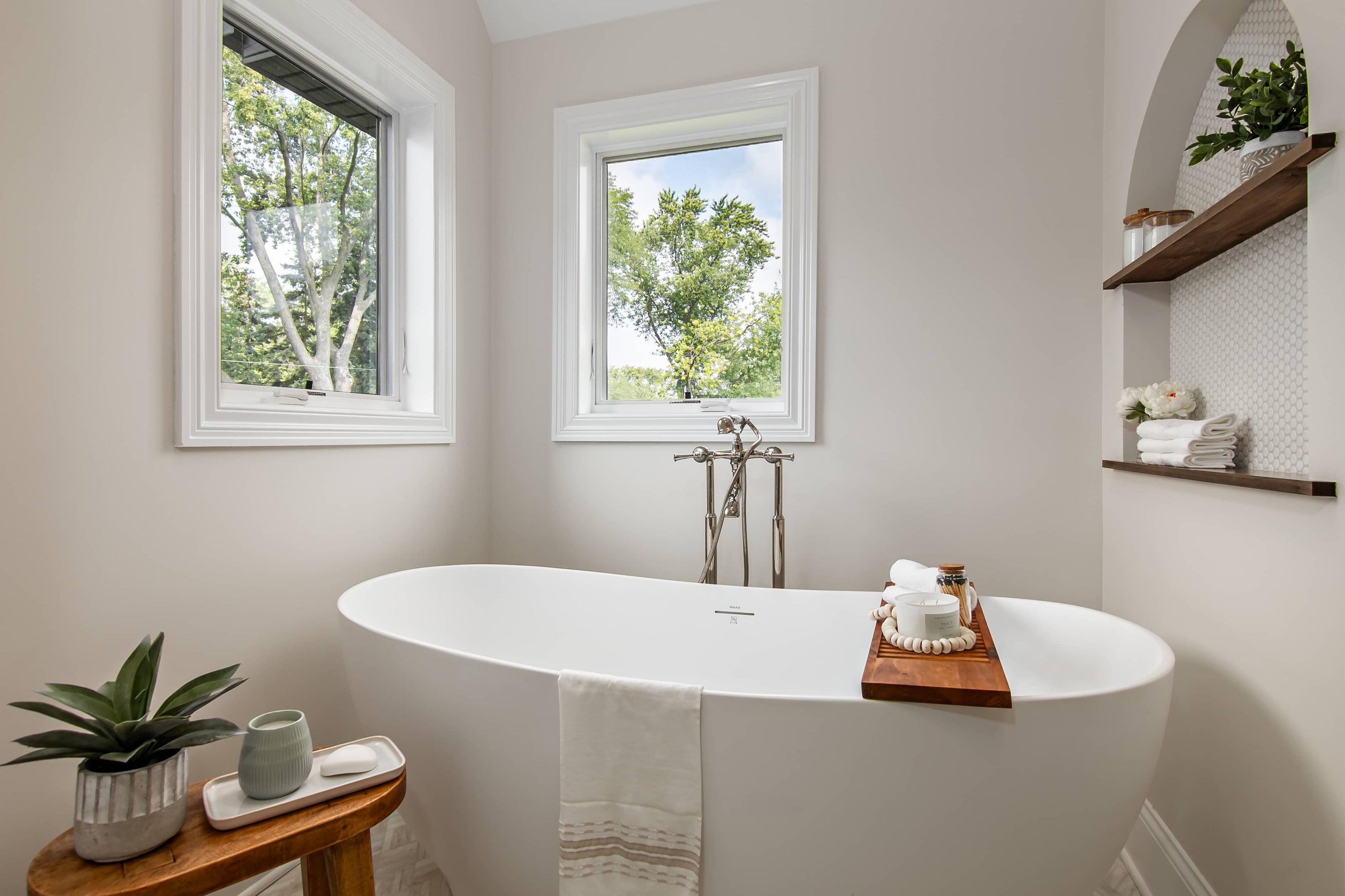 Modern bathroom with a freestanding bathtub, wooden shelf, and window views