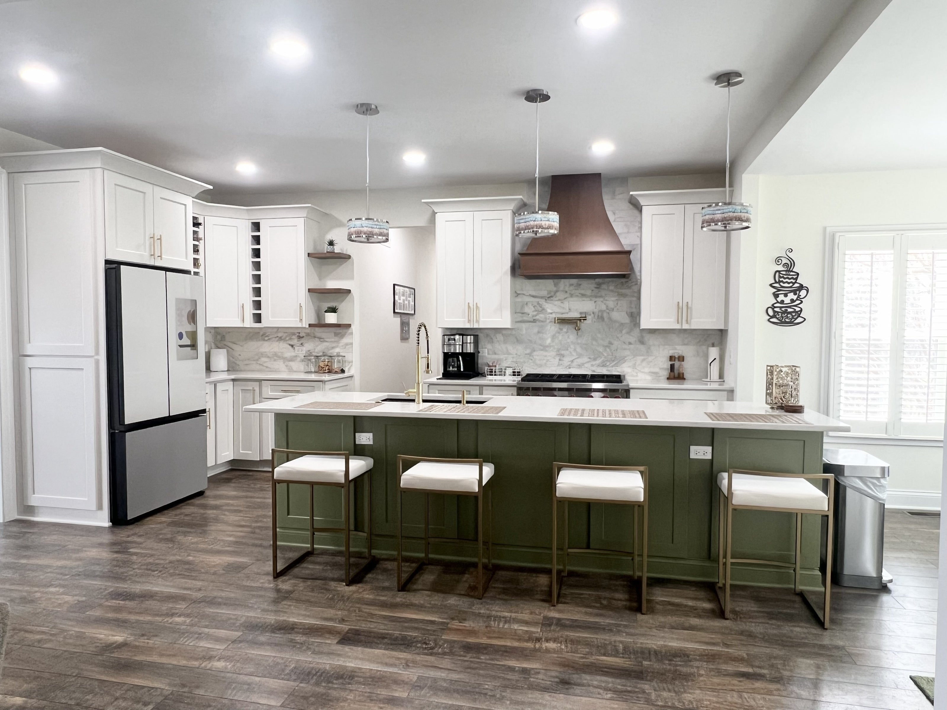 Modern kitchen with white cabinets, green island, and stainless steel appliances