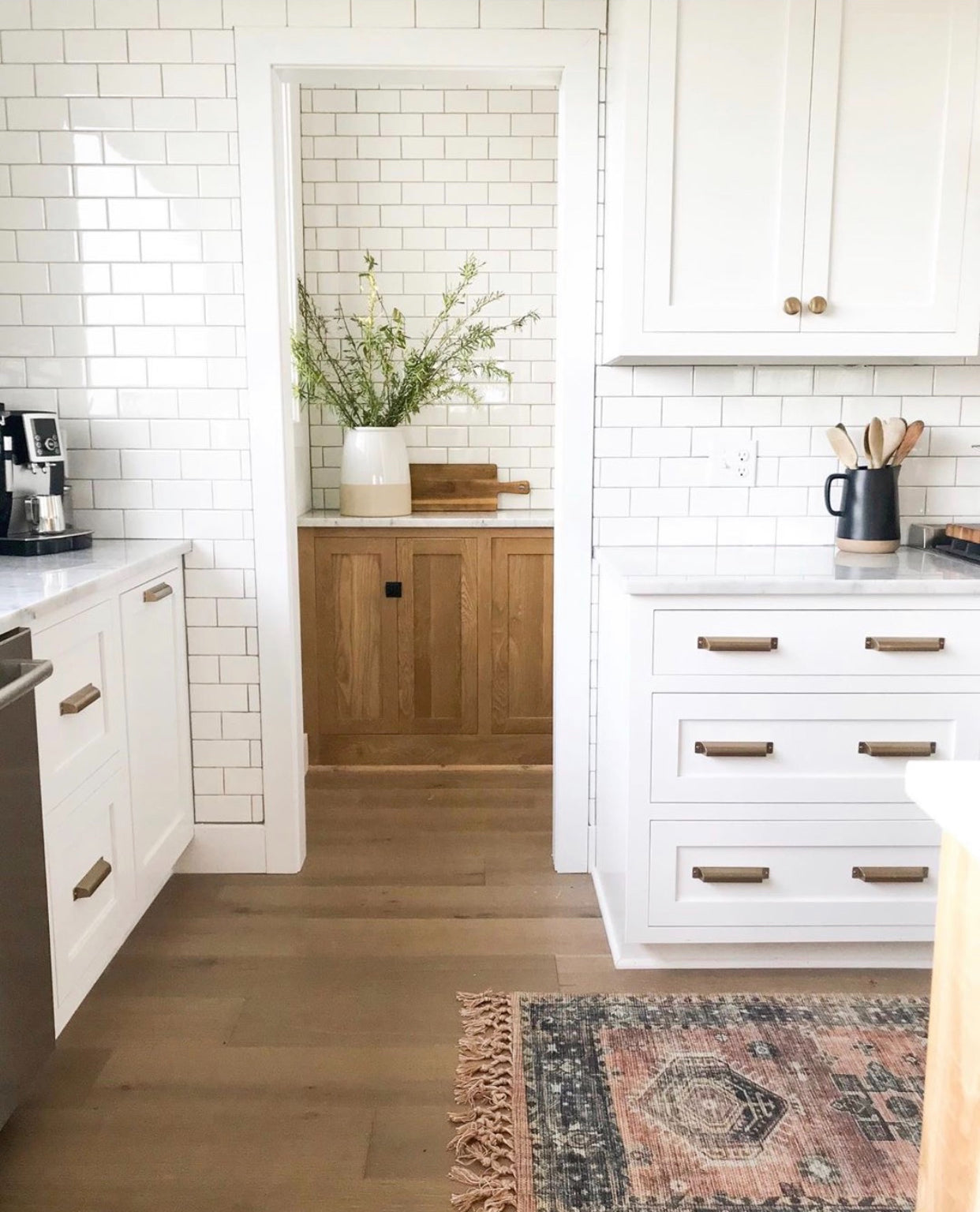 Modern kitchen with white cabinets, wooden floor, and decorative rug