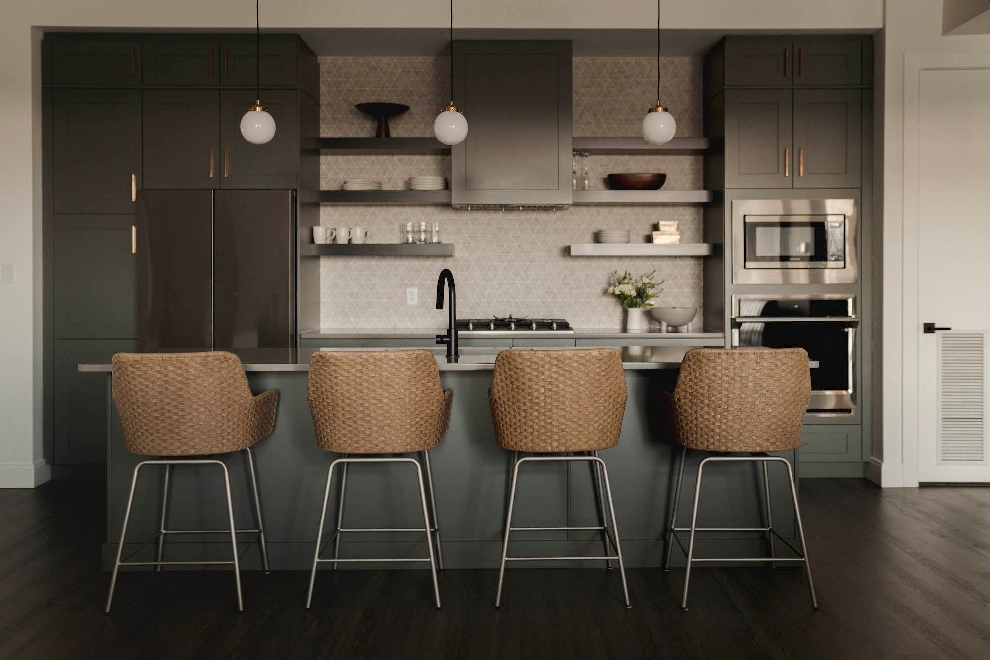 Modern kitchen with dark cabinets, stainless steel appliances, and four bar stools