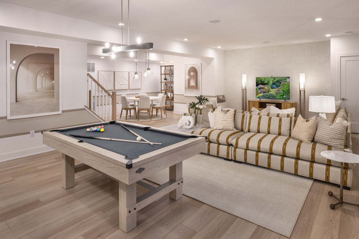 Finished basement with pool table, striped sectional sofa, and dining area