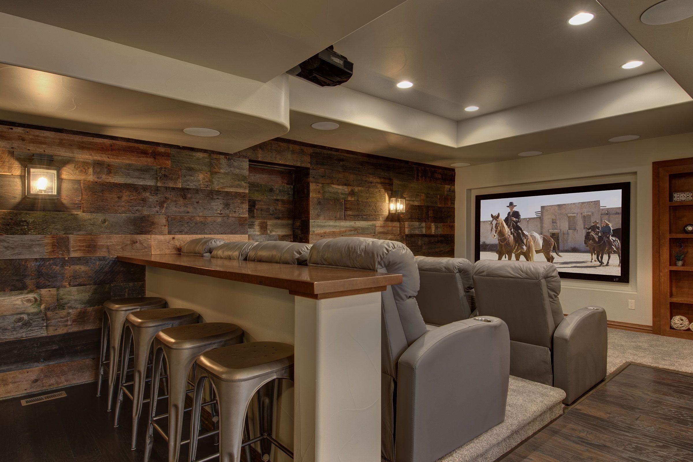 Home theater with recliner seats, bar stools, and a screen displaying a movie