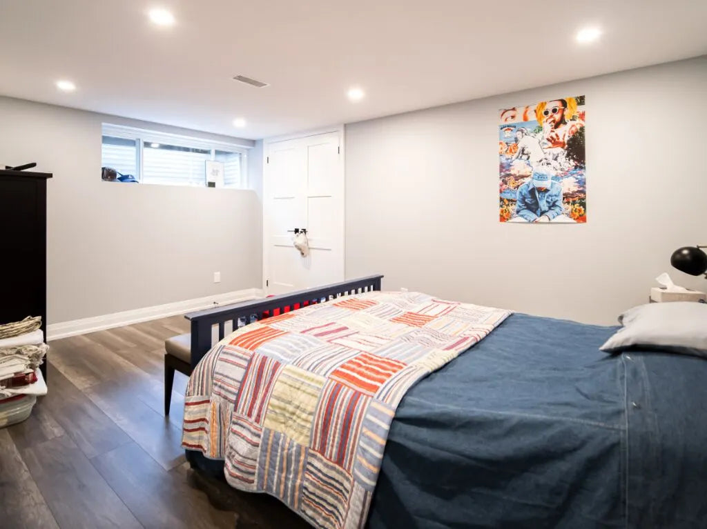 Bedroom with a bed, colorful blanket, and a poster on the wall